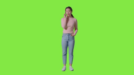 Full-Length-Studio-Shot-Of-Frustrated-Woman-Answering-Call-On-Mobile-Phone-Against-Green-Screen